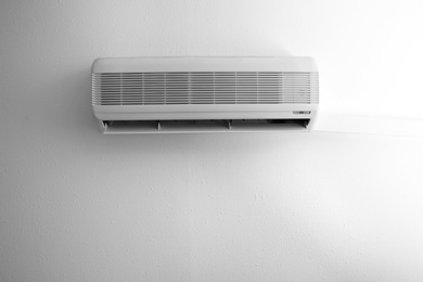 Photo of Modern air conditioner on white wall indoors