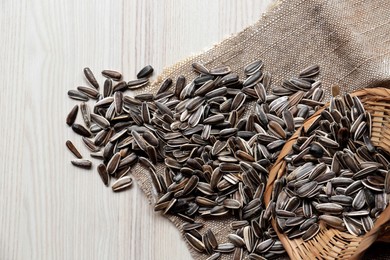 Sunflower seeds and cloth on wooden table, flat lay