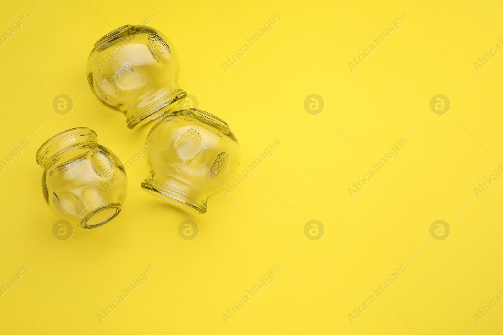 Photo of Glass cups on yellow background, flat lay and space for text. Cupping therapy