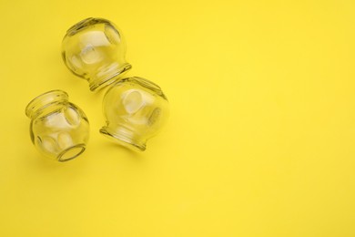 Photo of Glass cups on yellow background, flat lay and space for text. Cupping therapy