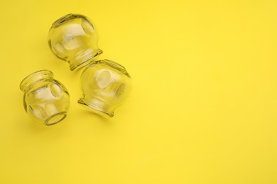 Glass cups on yellow background, flat lay and space for text. Cupping therapy