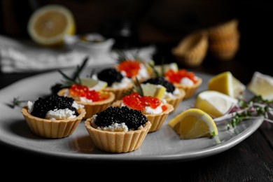 Delicious tartlets with red and black caviar served on table, closeup