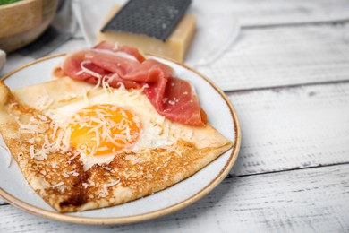 Delicious crepe with egg on white wooden table, closeup. Breton galette