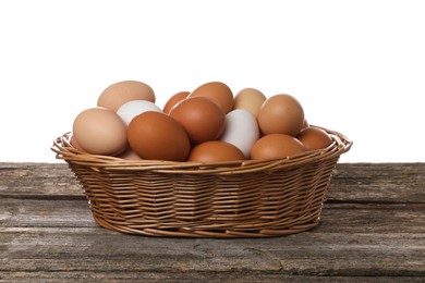 Photo of Fresh chicken eggs in wicker basket on wooden table against white background