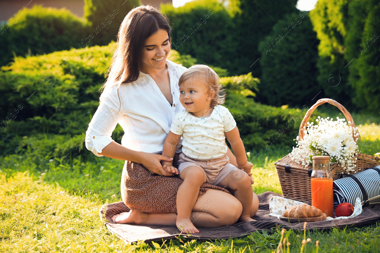 Photo of Mother with her baby daughter having picnic in garden on sunny day