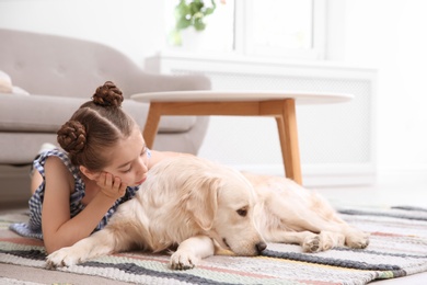 Photo of Cute little child with her pet on floor at home