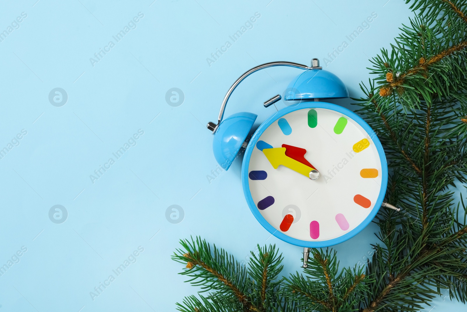 Photo of Alarm clock and fir branches on light blue background, flat lay with space for text. New Year countdown