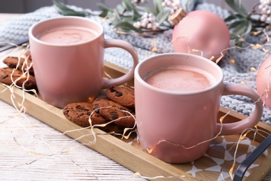 Tray with tasty cookies and cups of hot cocoa drink on table