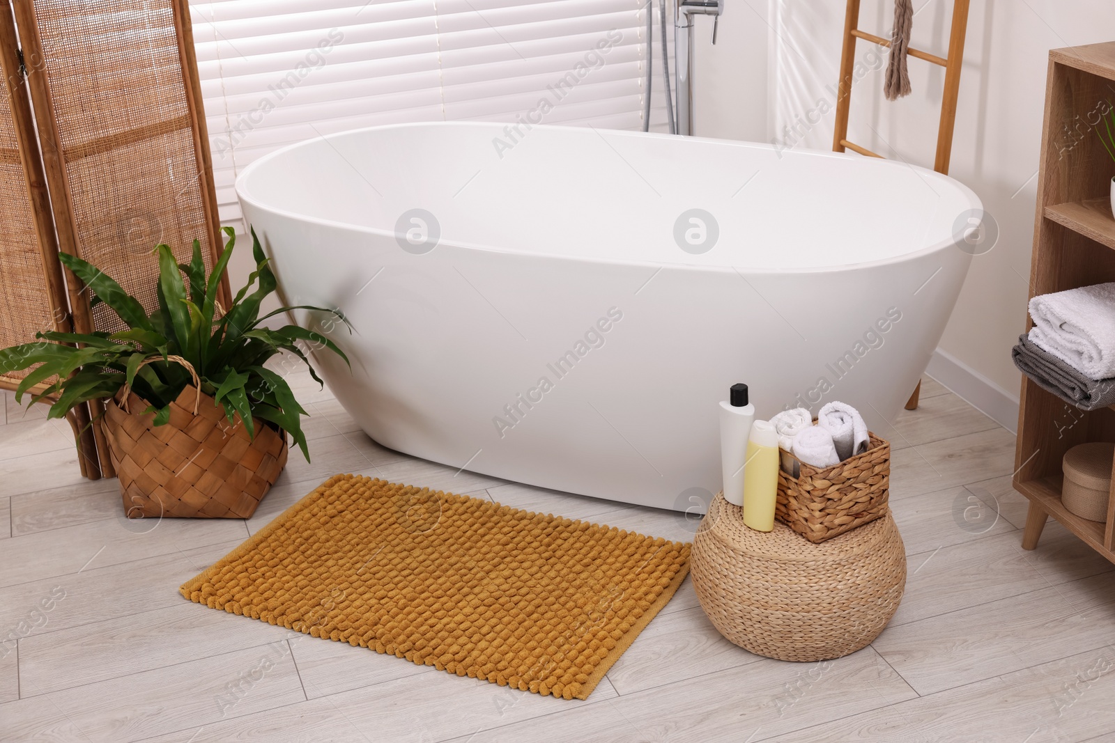 Photo of Stylish bathroom interior with soft bath mat and tub