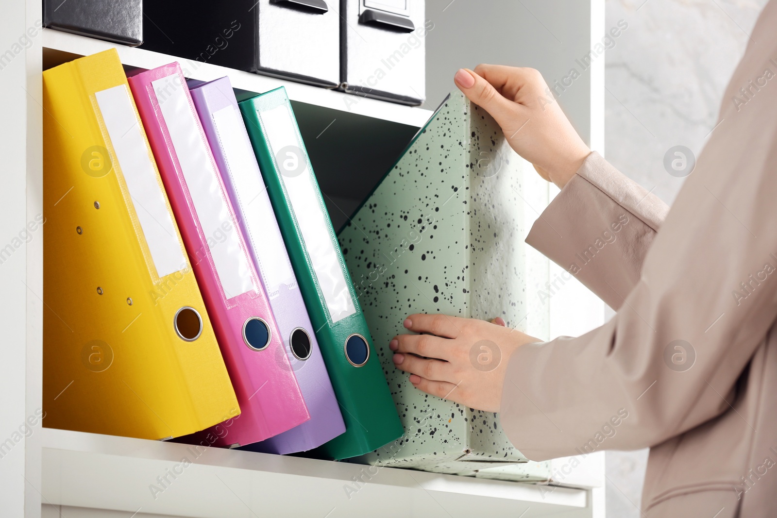 Photo of Woman taking folder from shelf in office, closeup