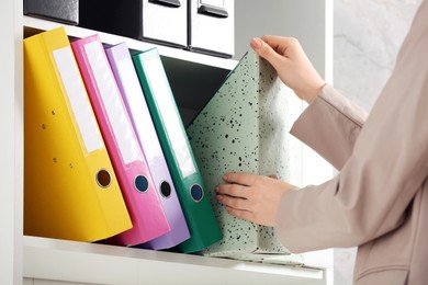Photo of Woman taking folder from shelf in office, closeup
