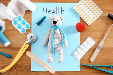 Flat lay composition with toy bear and medical items on wooden background. Children's doctor