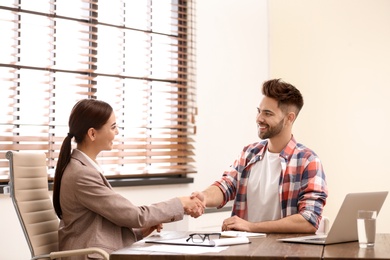 Female insurance agent shaking hands with client in office