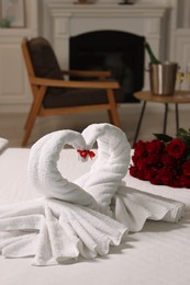 Honeymoon. Swans made of towels and beautiful red roses on bed in room