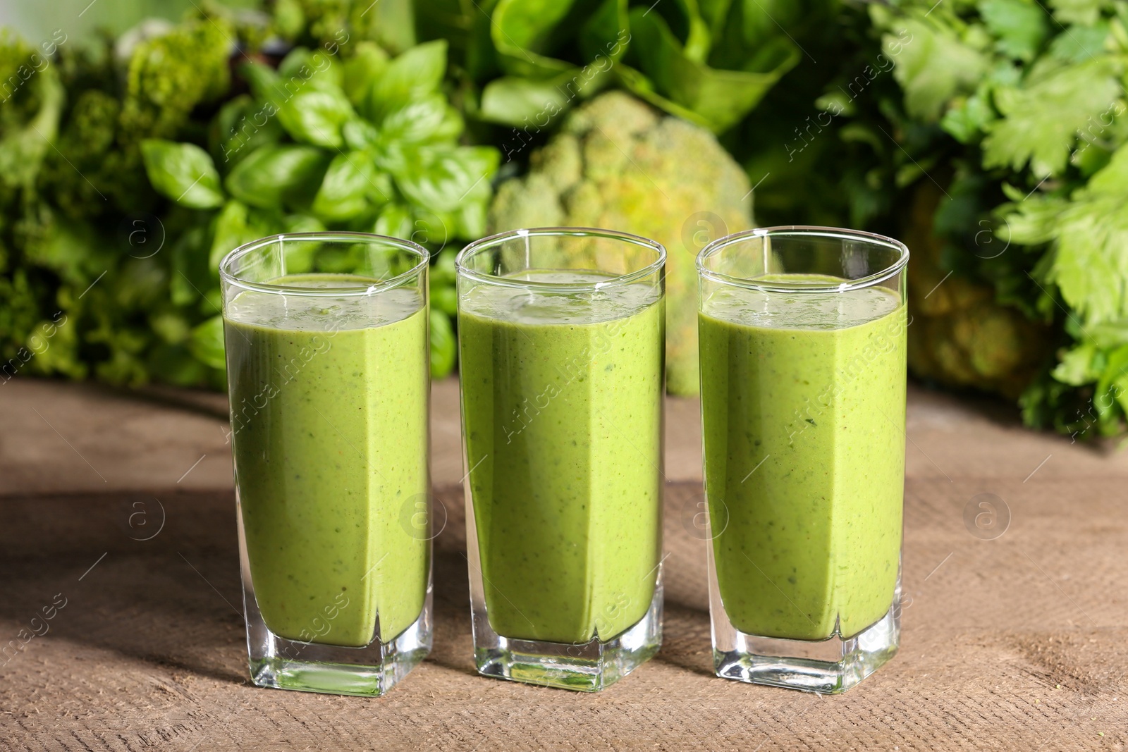 Photo of Glasses of fresh green smoothie and ingredients on wooden table