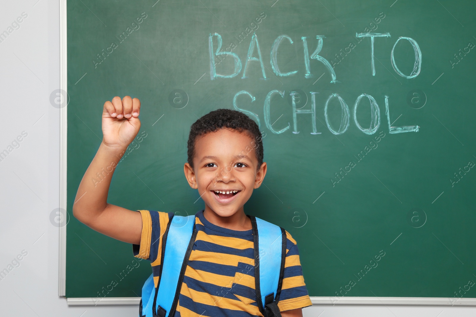 Photo of Little African-American child near chalkboard with text BACK TO SCHOOL