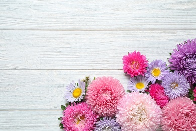 Photo of Flat lay composition with beautiful aster flowers on white wooden table. Space for text