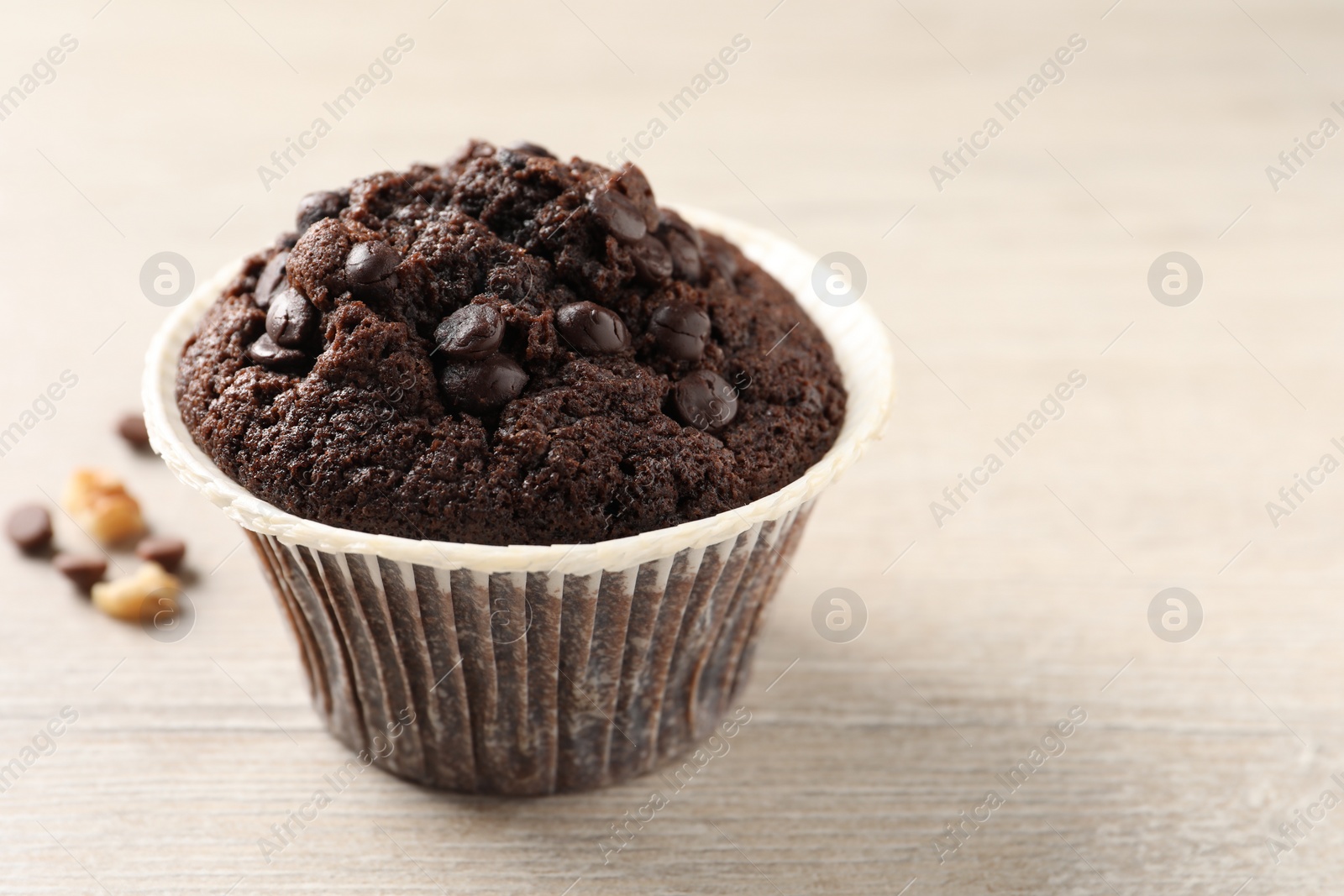 Photo of Delicious chocolate muffin on white wooden table, closeup and space for text