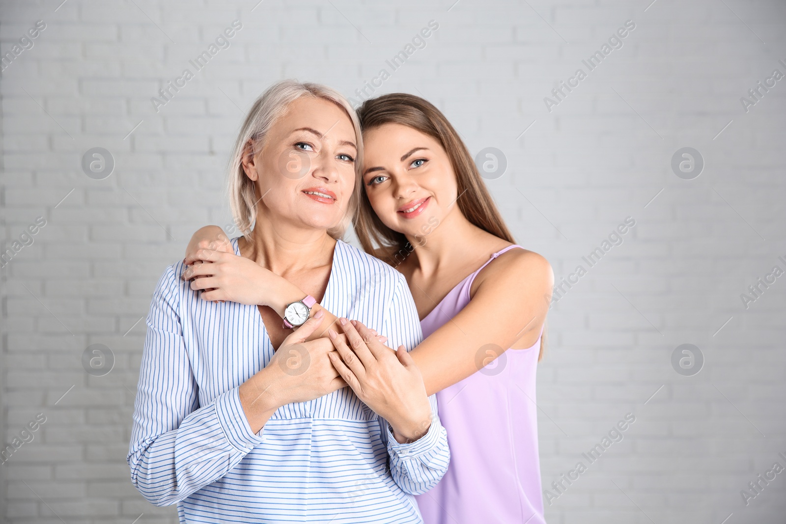 Photo of Portrait of young woman with her mature mother near brick wall