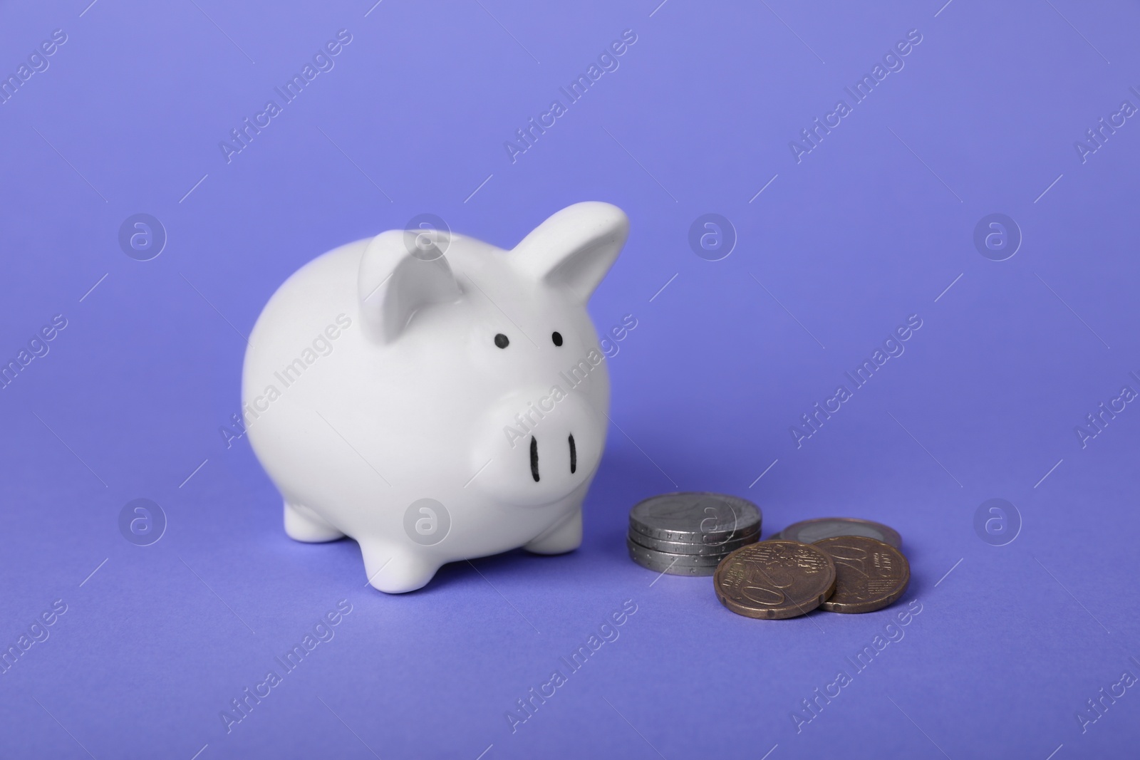 Photo of Ceramic piggy bank and coins on purple background. Financial savings