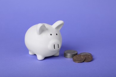 Photo of Ceramic piggy bank and coins on purple background. Financial savings