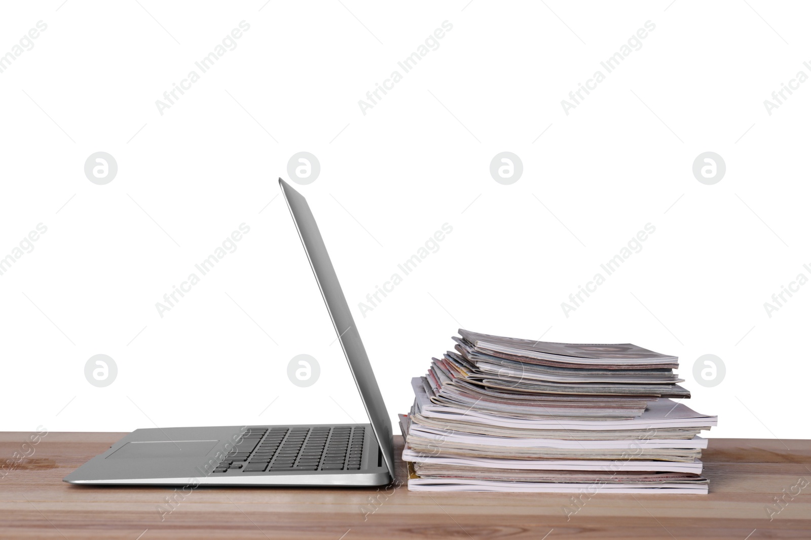 Photo of Laptop and stack of magazines on wooden table