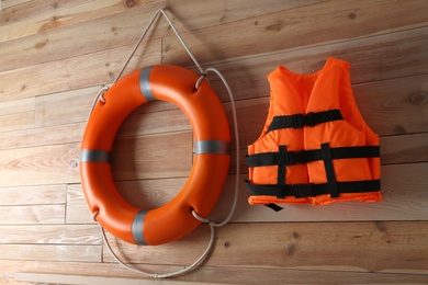 Orange life jacket and lifebuoy on  wooden background. Rescue equipment