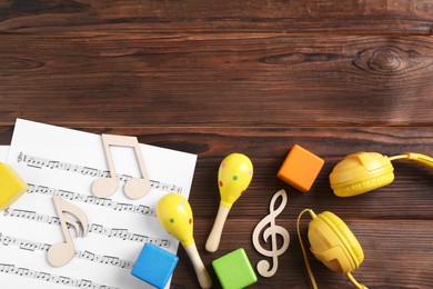 Photo of Baby song concept. Wooden notes, music sheet, headphones and toys on table, flat lay. Space for text