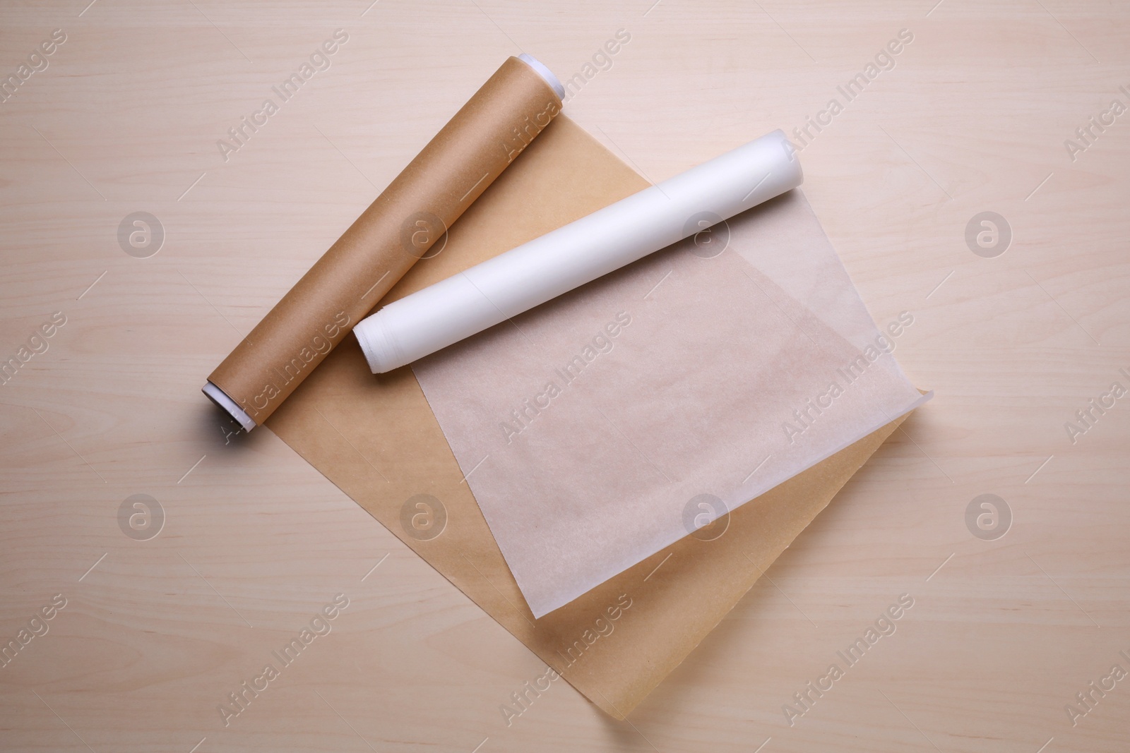 Photo of Rolls of baking paper on wooden table, flat lay
