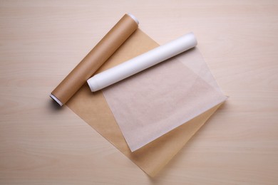 Photo of Rolls of baking paper on wooden table, flat lay