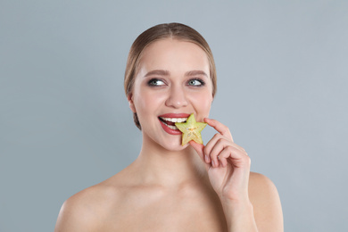 Photo of Young woman with slice of carambola on grey background. Vitamin rich food