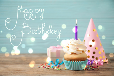 Image of Composition with cupcake on wooden table. Happy Birthday