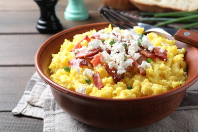 Photo of Tasty banosh served with brynza and pork cracklings in bowl on wooden table, closeup. Traditional Ukrainian dish