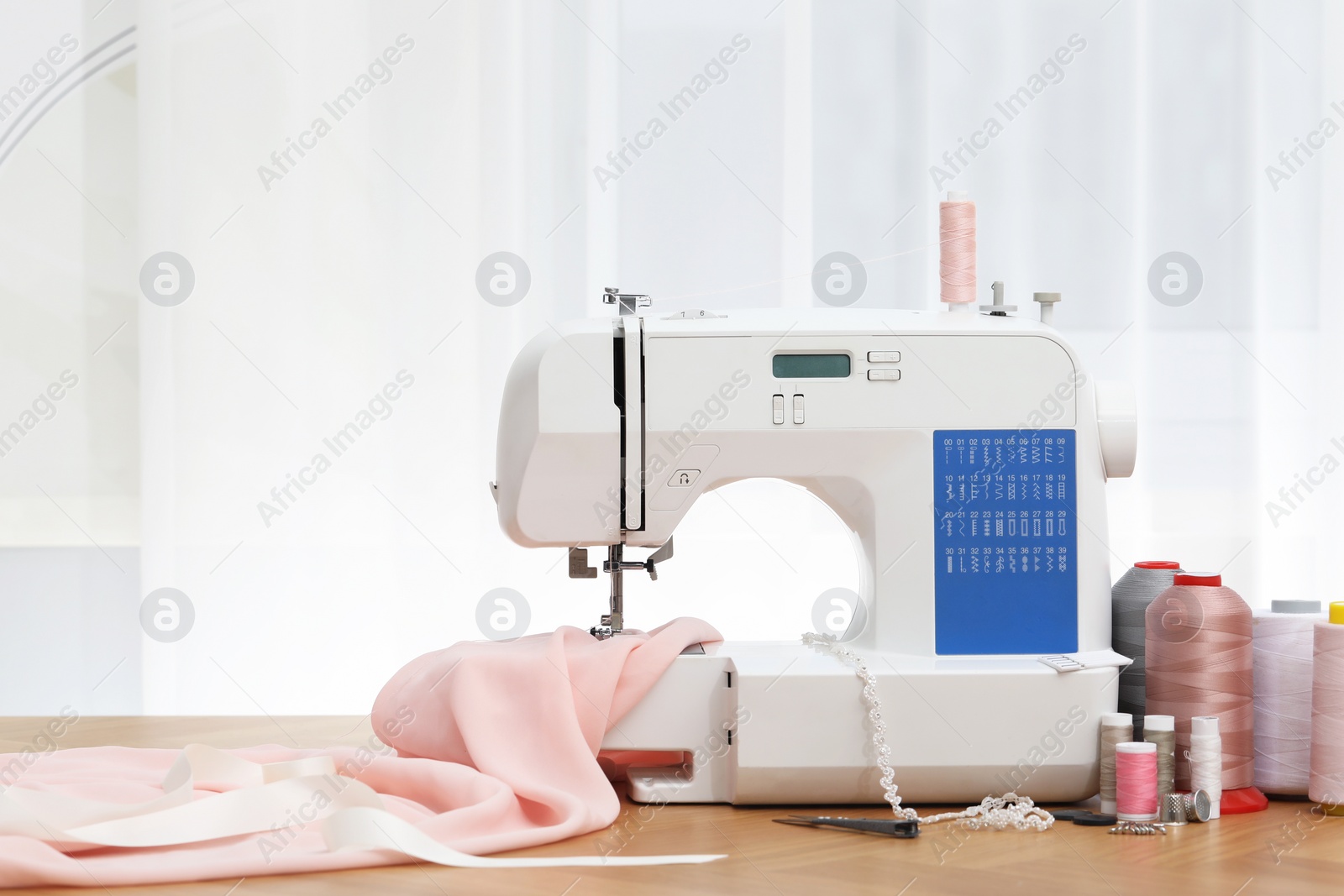 Photo of Sewing machine with fabric and craft accessories on wooden table indoors