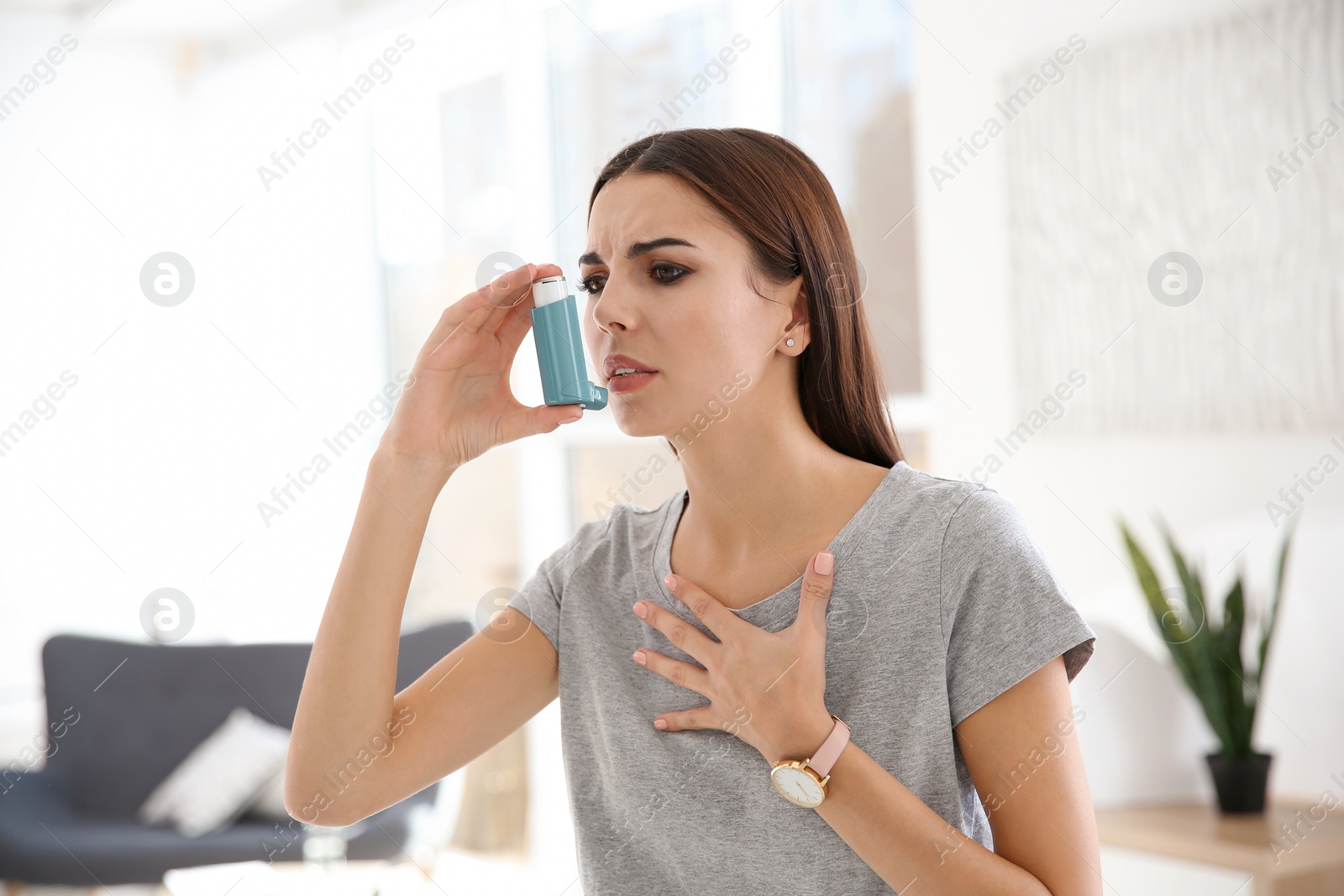 Photo of Young woman with asthma inhaler in light room