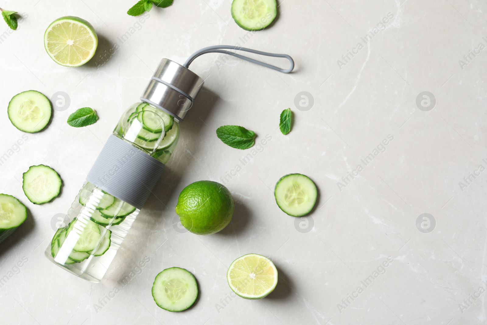 Photo of Flat lay composition with bottle of fresh cucumber water on grey background. Space for text