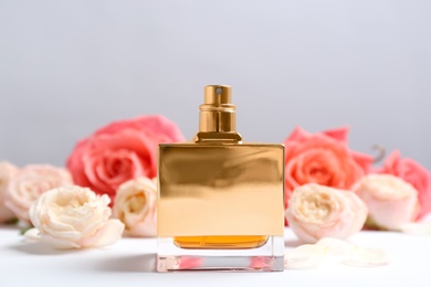 Bottle of perfume with beautiful roses on table