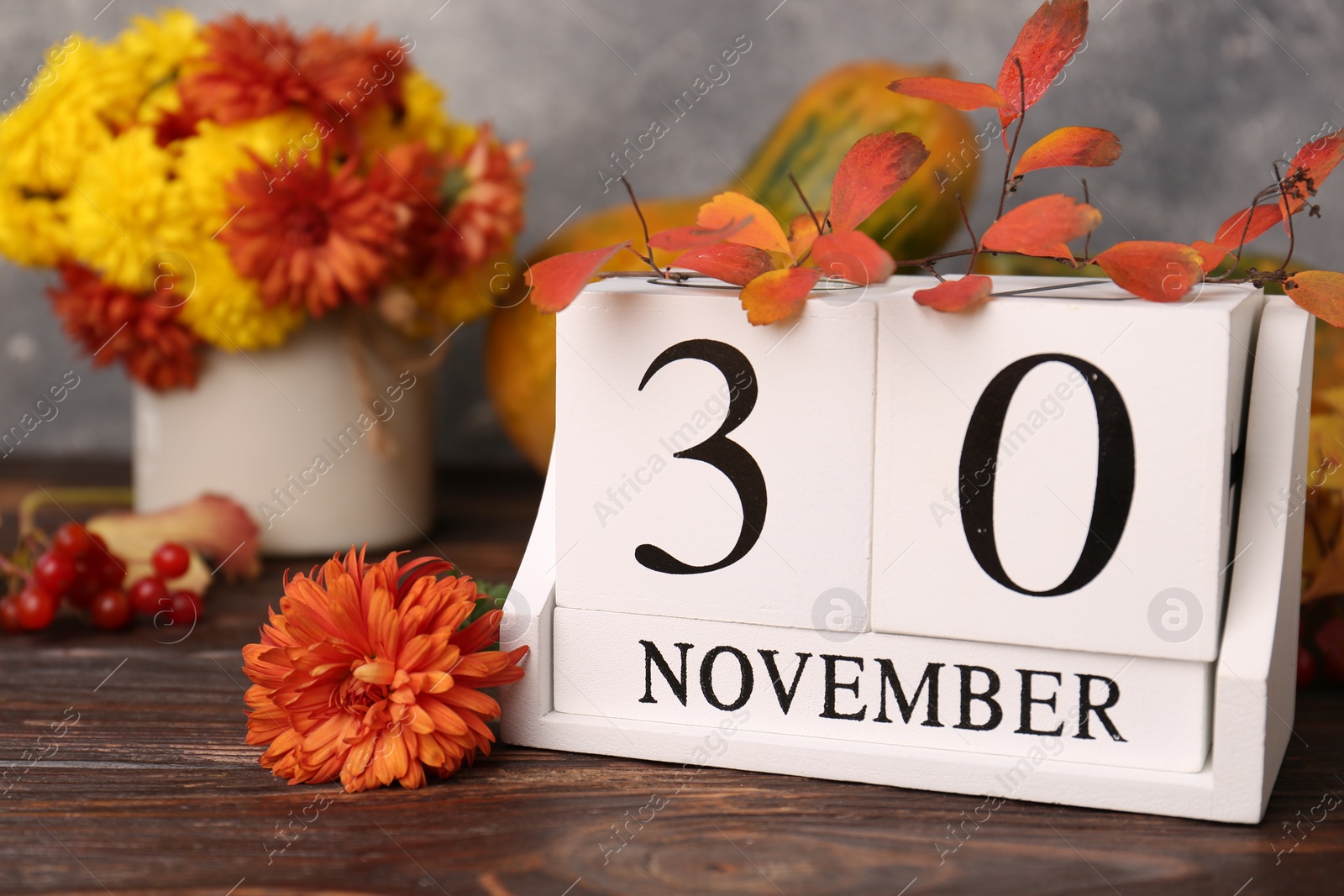 Photo of Thanksgiving day, holiday celebrated every fourth Thursday in November. Block calendar and autumn leaves on wooden table, closeup