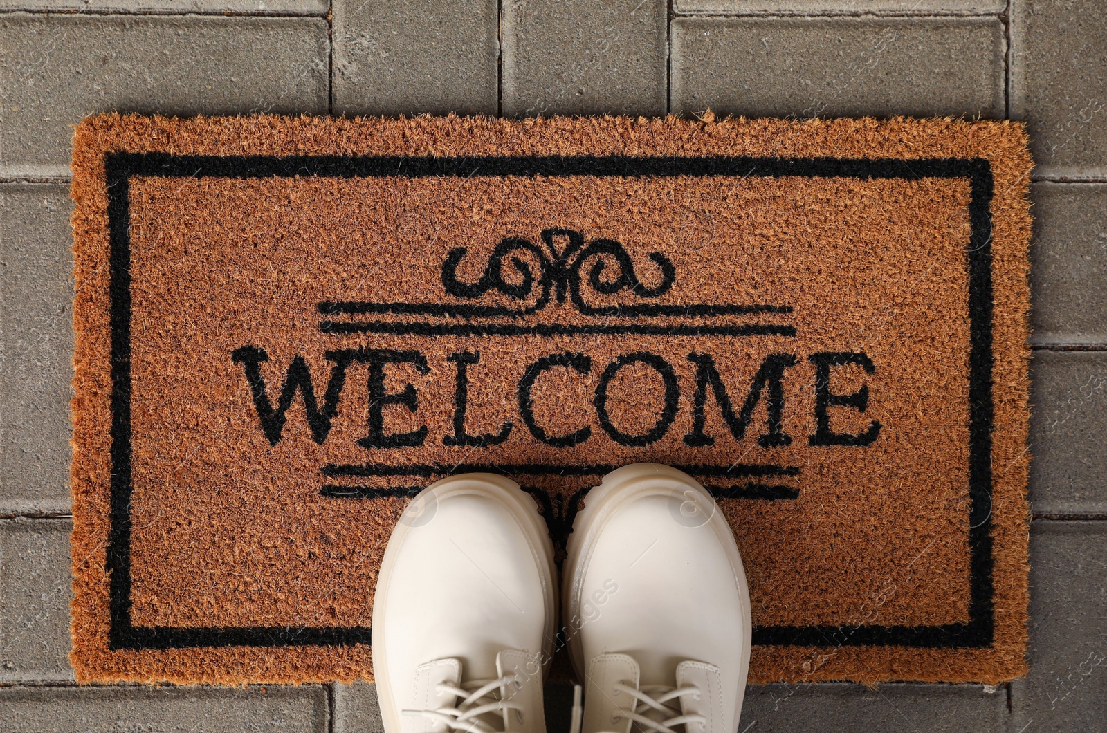 Photo of Door mat with word Welcome and stylish boots on floor, flat lay