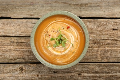 Photo of Delicious pumpkin soup with microgreens in bowl on wooden table, top view