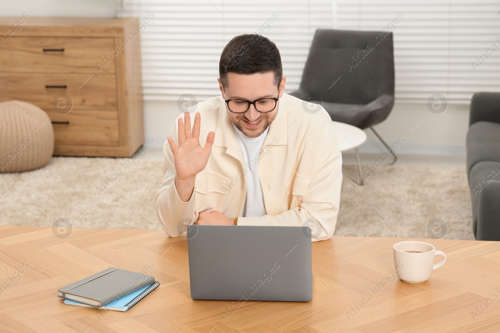 Photo of Man having video chat via laptop at wooden table at home