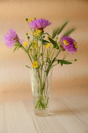 Photo of Bouquet of beautiful wildflowers in glass vase on wooden table