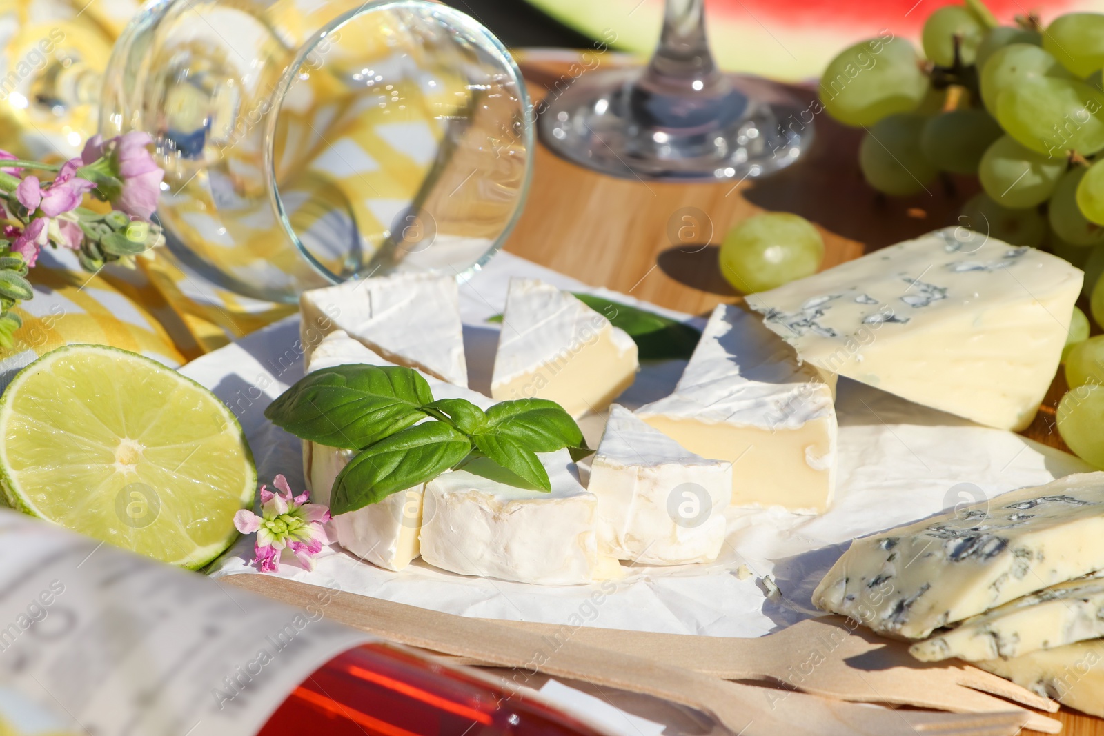 Photo of Delicious cheeses with basil and fruits on picnic blanket, closeup