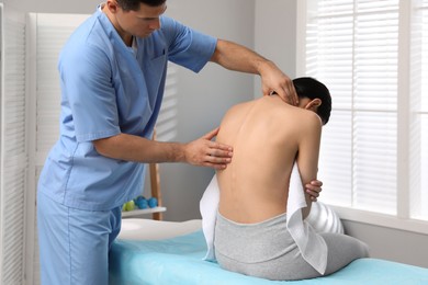 Photo of Orthopedist examining woman's back in clinic. Scoliosis treatment