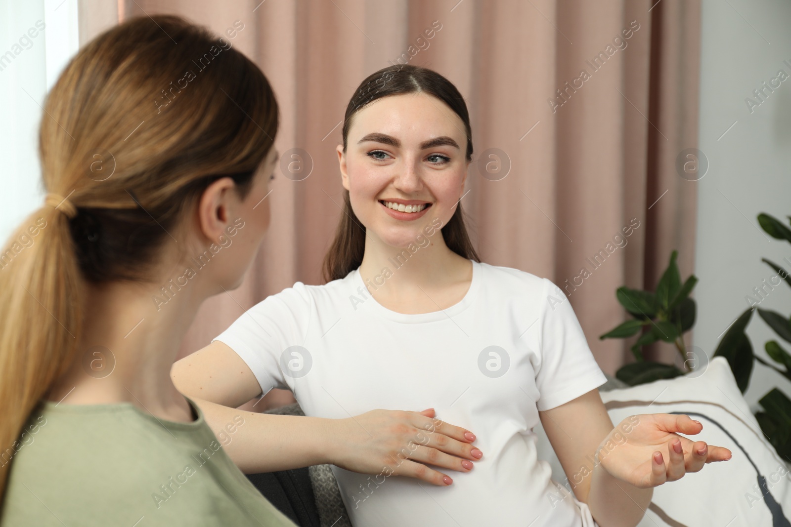 Photo of Doula working with pregnant woman on sofa at home. Preparation for child birth