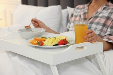 Photo of Young woman having breakfast on bed at home, closeup