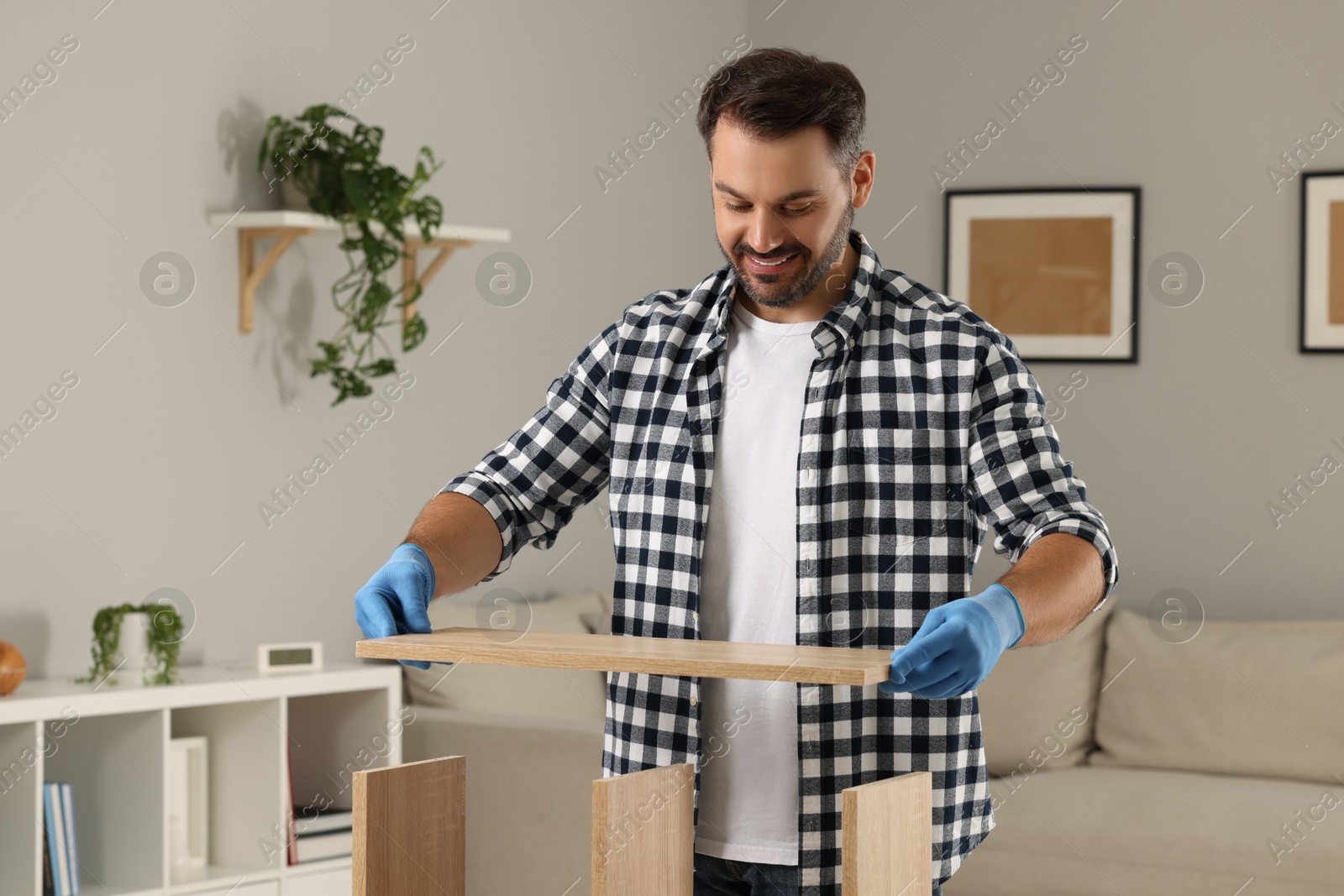 Photo of Man assembling wooden furniture in living room