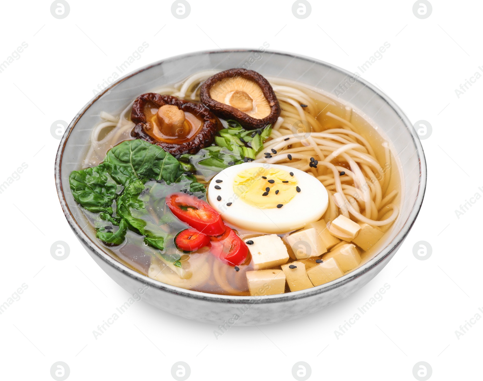 Photo of Delicious vegetarian ramen with egg, mushrooms, tofu and vegetables in bowl isolated on white. Noodle soup