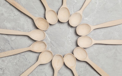 Frame of wooden spoons on grey marble table, flat lay. Cooking utensils