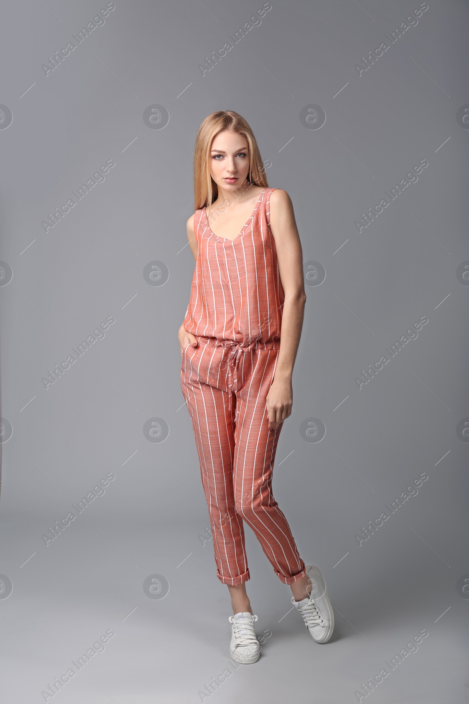 Photo of Young stylish woman in trendy sport shoes on grey background